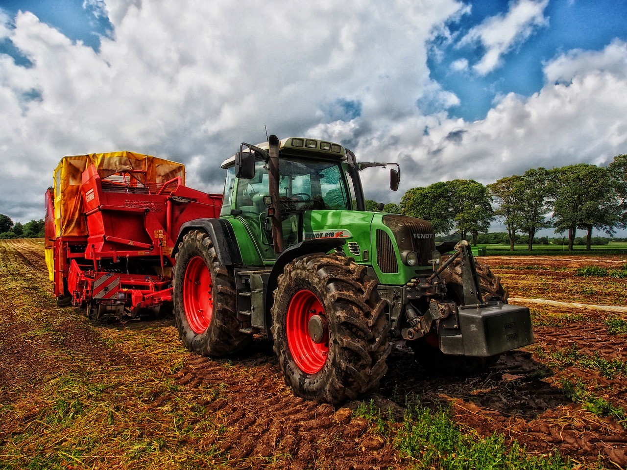 Na zdjęciu widoczny jest duży, zielony traktor, ktory wykonuje prace na polu.