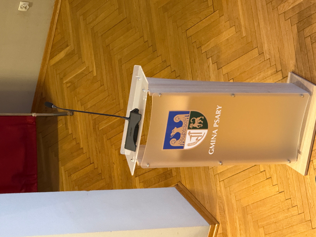 Grafika przedstawia mównicę z mikrofonem