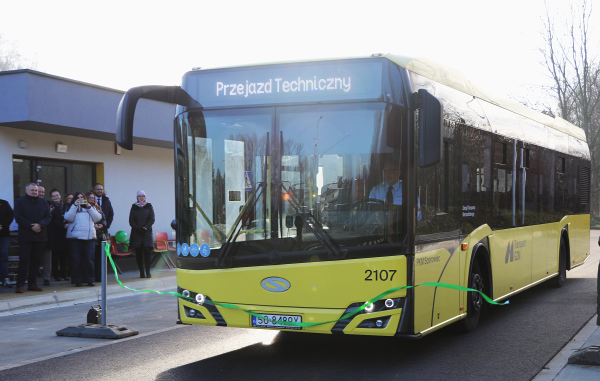 Zdjęcie przedstawia autobus przecinający wstęgę